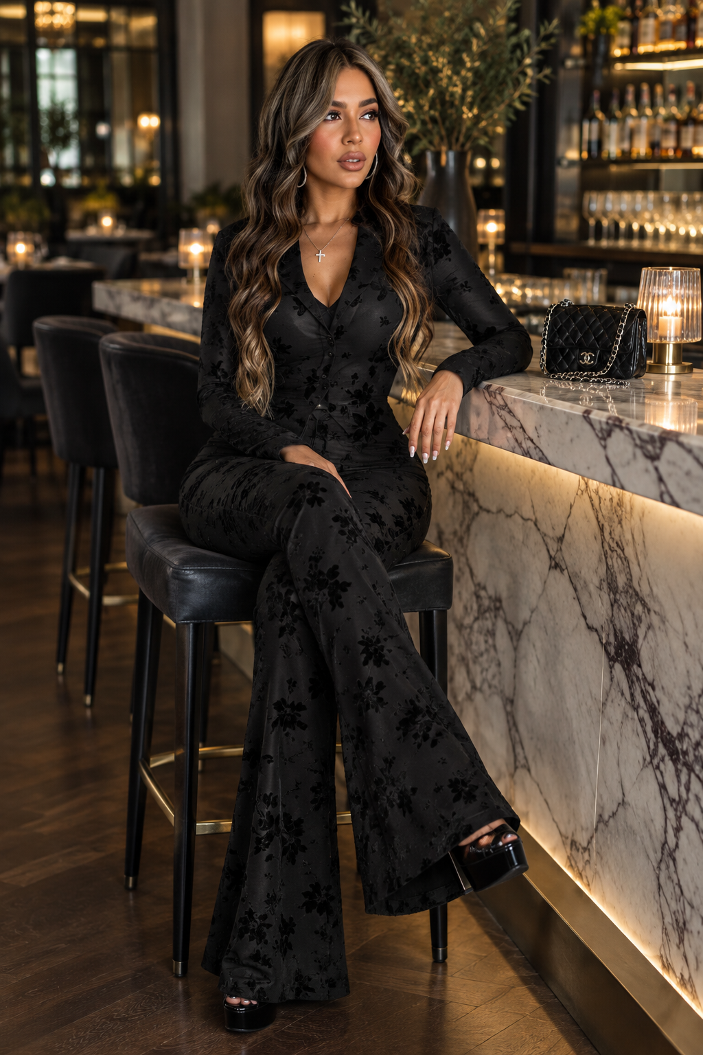 South Asian woman in the black floral pants suit at a marble restaurant bar